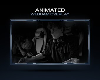 May include: A black and white image of a person wearing a black shirt and headphones, sitting in a chair in front of a computer. The image is framed in a blue and grey border with the text "ANIMATED WEBCAM OVERLAY" at the top.