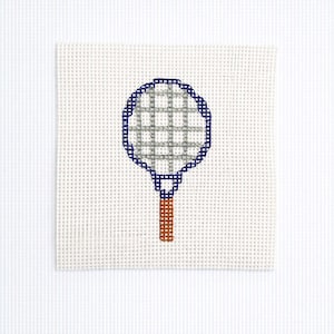May include: A cross-stitched tennis racket design on a white canvas. The racket head is gray with a blue border, and the handle is brown. The background is a white, textured fabric.