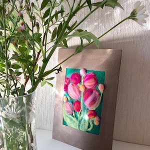 Peut inclure: Une œuvre d'art en feutre encadrée représentant des tulipes roses et rouges sur un fond vert. L'œuvre est dans un cadre marron et est exposée à côté d'un vase en verre transparent avec des fleurs et de la verdure.