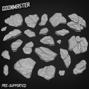 May include: A collection of gray, irregularly shaped rocks, varying in size, are scattered against a dark background. The rocks have a textured appearance, with visible cracks and crevices. The text "GOONMASTER" and "PRE-SUPPORTED" are displayed in white.