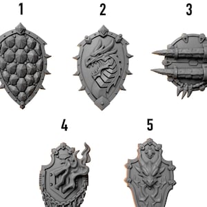 May include: Five gray shields with different designs. The shields are numbered 1 through 5. The shields have various features, including spikes, dragon heads, and flame designs. The text "GREYTIDE STUDIO" and "Shields" are at the top.