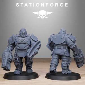 May include: A gray plastic miniature figure of a soldier wearing futuristic armor and holding a large gun. The figure is standing on a gray base.