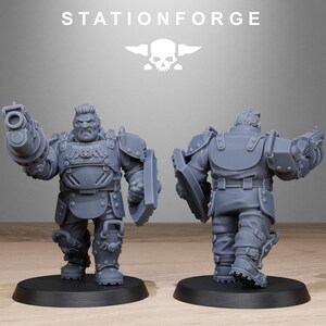 May include: Two gray plastic miniature figures of a soldier wearing armor and holding a weapon. The figure on the left is holding a large gun and a shield. The figure on the right is holding a shield and has its back to the viewer.