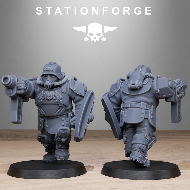 May include: Two gray plastic miniature figures of soldiers wearing futuristic armor and helmets. One figure is holding a gun and the other is holding a shield.