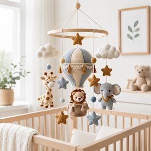 May include: A nursery mobile featuring a central crocheted hot air balloon with a lion in the basket, surrounded by hanging crocheted elements including a giraffe, an elephant, white clouds, and several mustard yellow and blue stars.