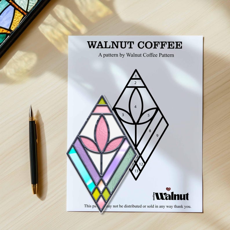 May include: A stained glass pattern of a flower with a pink center, surrounded by purple, blue, green, and yellow glass. The pattern is on a white background with the text "WALNUT COFFEE" and "A pattern by Walnut Coffee Pattern".
