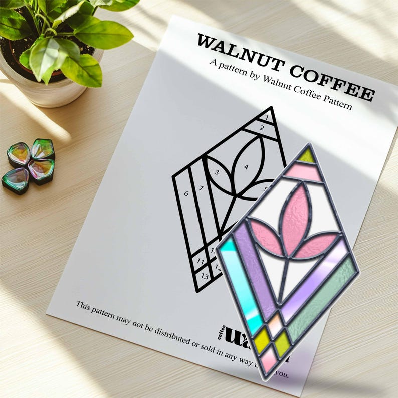 May include: A black and white stained glass pattern with numbers 1 through 13. A completed stained glass piece with a pink flower design and a rainbow of colors is shown next to the pattern.