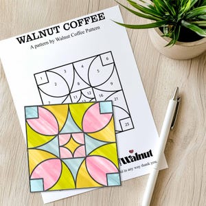 Può includere: Un modello stampabile per un blocco di trapunta in stile vetrata. Il modello si chiama "Walnut Coffee" ed è composto da 25 cerchi numerati. Il blocco finito è mostrato nell'immagine e presenta i colori rosa, giallo e blu.