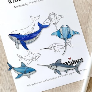 May include: A stained glass pattern featuring a whale, manta ray, shark, swordfish, and marlin. The pattern is numbered for easy assembly. The pattern is titled "Walnut".