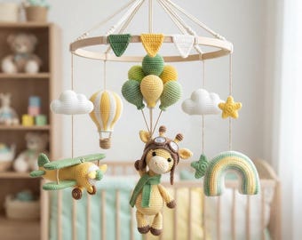 May include: A hanging nursery mobile featuring a circular wooden frame with crochet elements including a yellow airplane, a striped hot air balloon, a giraffe wearing aviator goggles, a rainbow, white clouds, stars, and a cluster of green and yellow balloons.