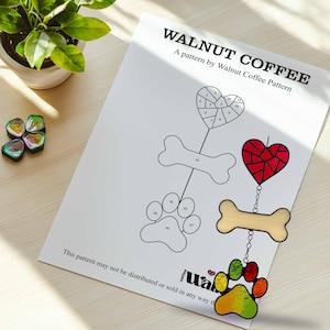 Op de afbeelding: Een printbaar patroon voor een gebrandschilderd zonnenvanger met een hart, een bot en een pootprint. Het patroon is getiteld "Walnut Coffee" en bevat genummerde onderdelen voor montage.