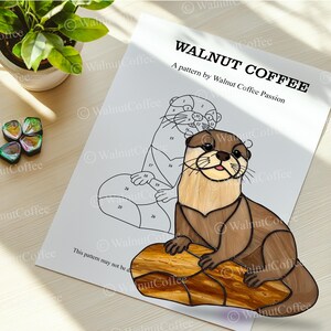 Puede incluir: Un patr&oacute;n de l&iacute;nea en blanco y negro de una nutria sentada en una roca. El patr&oacute;n est&aacute; numerado para un proyecto de pintura por n&uacute;meros. El texto "WALNUT COFFEE" y "A pattern by Walnut Coffee Passion" est&aacute; en la parte superior de la p&aacute;gina.