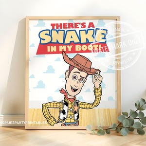 Könnte beinhalten: Ein gerahmter Druck mit einer Cartoon-Cowboy-Figur, die einen braunen Hut, ein gelbes kariertes Hemd und eine Weste mit Kuhflecken trägt. Der Text lautet THERE'S A SNAKE IN MY BOOT! vor einem hellblauen Hintergrund mit weißen Wolken.