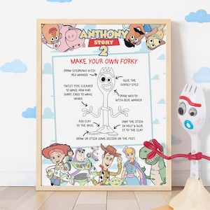 May include: A framed poster titled ANTHONY STORY 2 featuring Toy Story characters and a Make Your Own Forky instructional guide with text and line art. Beside the frame stands a white plastic spork character with red pipe cleaner arms.