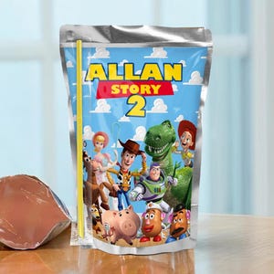 Pode incluir: Uma bolsa de bebida flexível em tom prateado com um fundo de céu azul e nuvens brancas, com o texto ALLAN STORY 2 em amarelo e vermelho. A bolsa exibe um grupo de personagens animados, incluindo um cowboy, um patrulheiro espacial e um dinossauro.