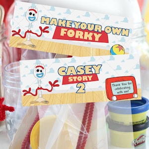 K&ouml;nnte beinhalten: Eine wei&szlig;e Plastikgabel, die in einen Forky-Charakter verwandelt wurde, mit roten Pfeifenreinigerarmen und einer gelben Basis. Zwei Karten lesen "Make Your Own Forky" und "Casey Story 2". Weitere Bastelmaterialien sind sichtbar.