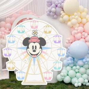 以下が含まれることがあります： パステルカラーのゴンドラと中央にミニーマウスの頭が付いた白と金の観覧車。観覧車はパステルカラーの風船で囲まれています。