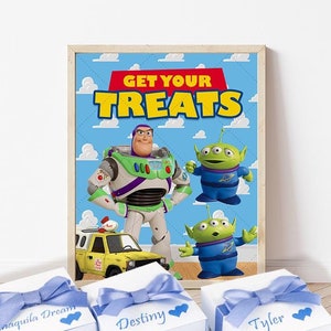 Può includere: Tre scatole regalo bianche con fiocchi blu e nomi personalizzati. Le scatole sono davanti a un poster incorniciato con sfondo blu e il testo "GET YOUR TREATS". Il poster presenta personaggi del film Toy Story, tra cui Buzz Lightyear e l'alieno.