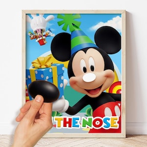 Può includere: Un poster incorniciato con Topolino che indossa un cappellino da festa blu e verde, mentre tiene in mano un pacco regalo blu con nastri gialli. Sullo sfondo, Minnie e Paperino appaiono in una mongolfiera. Il testo recita PIN THE NOSE.