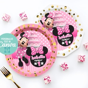 Könnte beinhalten: Zwei runde Pappteller mit einem rosa-weißen Punktemuster, Minnie Maus, einer Torte und dem Text Isabella turns 1. Die Teller haben einen Rand aus goldenen Punkten und sind von kleinen quadratischen rosa-weißen Leckereien umgeben.