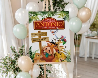 May include: A party welcome sign on an easel, featuring a colorful illustration of characters from The Lion King. The sign reads "Our Little King Antonio is on the Way!" and "Welcome to Our Party!" with balloons in the background.