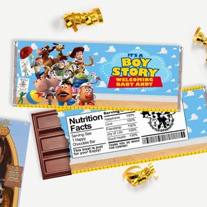 May include: A rectangular chocolate bar wrapper featuring Toy Story characters, the text IT'S A BOY STORY WELCOMING BABY ANDY, and a nutrition facts label listing Happiness, Love, Friendship, Joy of Life, and Good Health at 100% serving size.