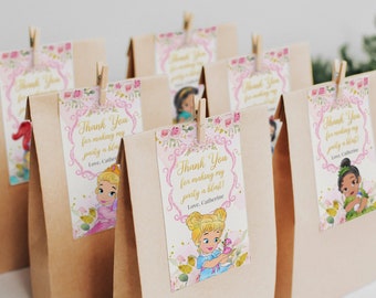Peut inclure: Sacs cadeaux de remerciement roses et dorés avec des illustrations de princesses et le texte "Merci d'avoir fait de ma fête un succès ! Avec amour, Catherine".