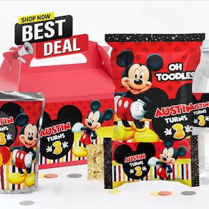 Peut inclure: Une boîte à cadeaux rose, une poche de jus, un sachet de snacks, une barre de céréales et une bouteille d'eau, avec des motifs de Mickey Mouse, le texte "Austin Turns 3" et "Oh Toodles". Un panneau "Shop Now Best Deal" avec un mégaphone.