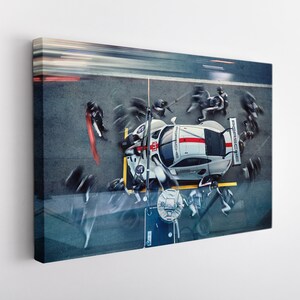 May include: A white and red race car with the word "Porsche" on the side is being worked on by a pit crew. The car is on a racetrack with a blurred background.
