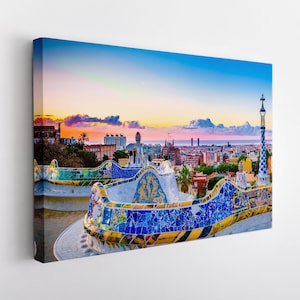 May include: A colorful mosaic bench overlooking a cityscape at sunset. The bench is made of blue, yellow, and white tiles. The city skyline is in the background, with the sea visible in the distance.