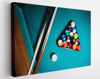 May include: A green felt pool table with two wooden cues and a triangle rack of billiard balls. The balls are arranged in a pyramid shape and include the numbers 1 through 15.