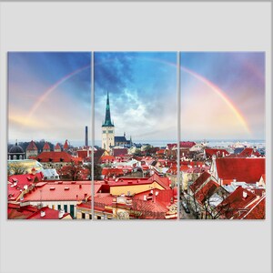 May include: A panoramic view of a city with red rooftops and a tall church steeple. A rainbow arches over the city, creating a colorful and picturesque scene.
