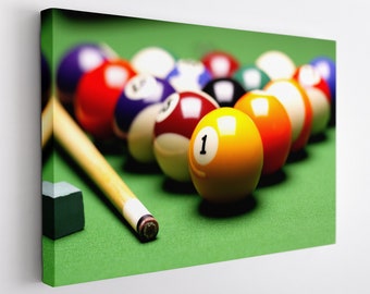 May include: A green felt pool table with a set of billiard balls arranged in a triangle formation. The balls are various colors, including red, yellow, blue, and black. A wooden pool cue is lying on the table next to the balls.