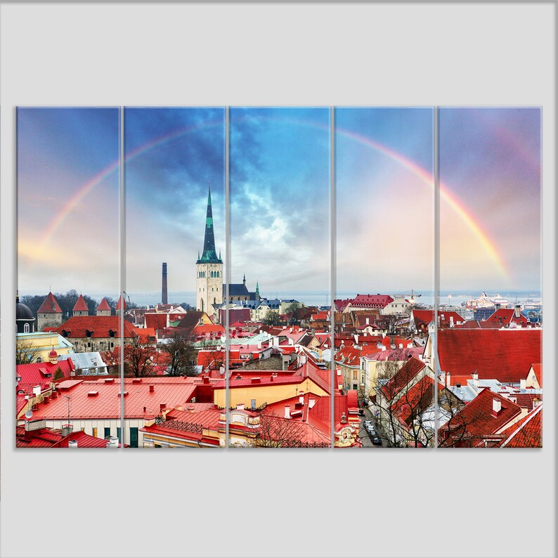 May include: A panoramic view of a city with red rooftops and a tall church steeple. A rainbow arches over the city, creating a colorful and vibrant scene.