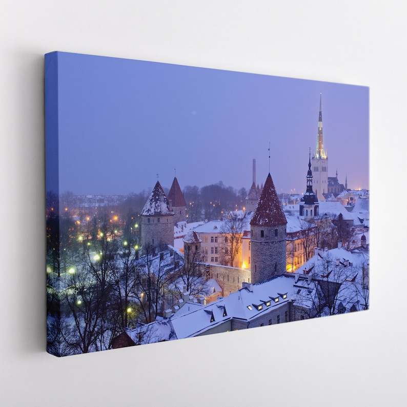 May include: A panoramic view of a snow-covered cityscape with a tall, pointed church spire in the background. The city is lit up with warm, yellow lights, and the sky is a soft, blue-purple colour.