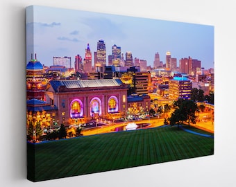 May include: A panoramic view of the Kansas City skyline at dusk, featuring the Union Station building in the foreground. The city lights illuminate the buildings and streets, creating a vibrant and colourful scene.