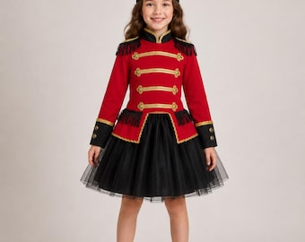 May include: A red and black soldier-style costume featuring a tall black hat with gold trim, a red jacket with gold braided detailing, black fringe epaulets, and a black tulle skirt. The jacket includes long sleeves with black cuffs and gold buttons.