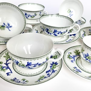 May include: Set of six white teacups and saucers with a blue and green floral pattern. The cups and saucers have a delicate, intricate design.