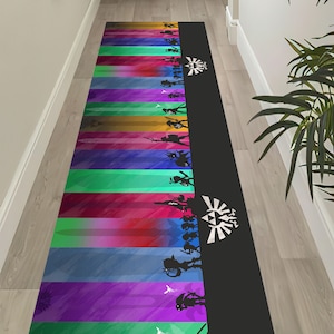May include: A long, rectangular rug with a black background and colourful vertical stripes. The stripes are a gradient of blue, purple, green, yellow, and orange. Silhouettes of characters from the Legend of Zelda video game series are on the right side of the rug, with the Triforce symbol at the top.