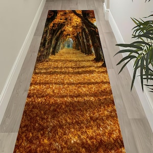 May include: A rectangular runner rug featuring a scenic autumn forest path. The rug displays a tunnel of trees with golden leaves, creating a warm, inviting atmosphere. The rug is designed to fit a hallway or entryway.
