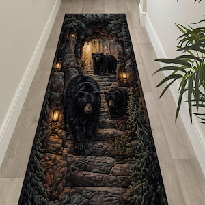 May include: A long, rectangular rug featuring a detailed illustration of three black bears ascending stone steps. The bears are set within a dark, forested cave scene, illuminated by warm lantern light. The rug is designed for a hallway or entryway.