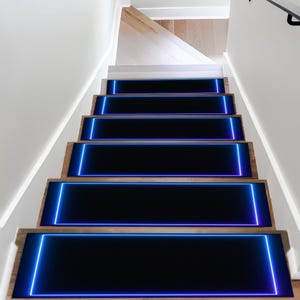 May include: A staircase with wooden treads and black risers. Each step has a bright blue neon light border, giving a modern and stylish look. The walls are white, and the overall design is clean and contemporary.
