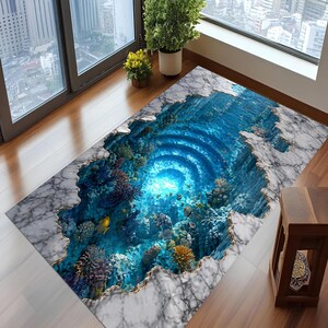 May include: A rectangular area rug with a 3D underwater scene design. The rug features a marble-like border with a gold trim, framing a deep blue ocean with coral, fish, and a glowing center. The rug is placed on a wooden floor.