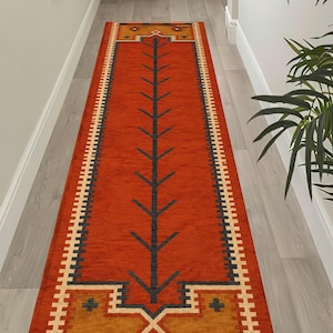 Può includere: Un lungo tappeto rettangolare da corridoio con un vivace centro color arancio bruciato e un motivo centrale a forma di albero grigio scuro. Le estremità sono decorate con pannelli giallo senape, rombi geometrici e un bordo color crema.