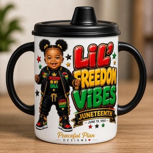May include: A white sippy cup with black handles and a black lid. The cup features a colorful illustration of a child in a black outfit with the text "Lil' Freedom Vibes Juneteenth" and "Freedom in my DNA". The cup also has the text "Peaceful Plan Designs".