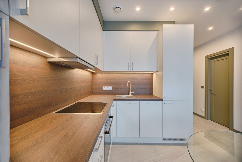 May include: A modern kitchen with white cabinets, a wood worktop, and a stainless steel sink. The kitchen has a wood backsplash with under-cabinet lighting.