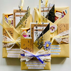 May include: Four brown paper packages wrapped with white lace and purple ribbon. Each package contains a book, a bookmark, and a small gift. The packages are decorated with dried flowers and the text "Reading List" and "Days I Read".