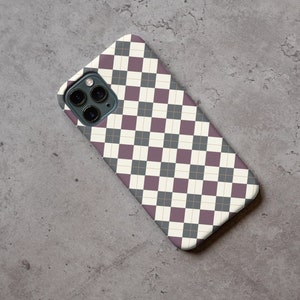 May include: A phone case with a black and white checkered pattern with a thin gold line running through the center of each square. The case has a camera lens cutout in the upper left corner.