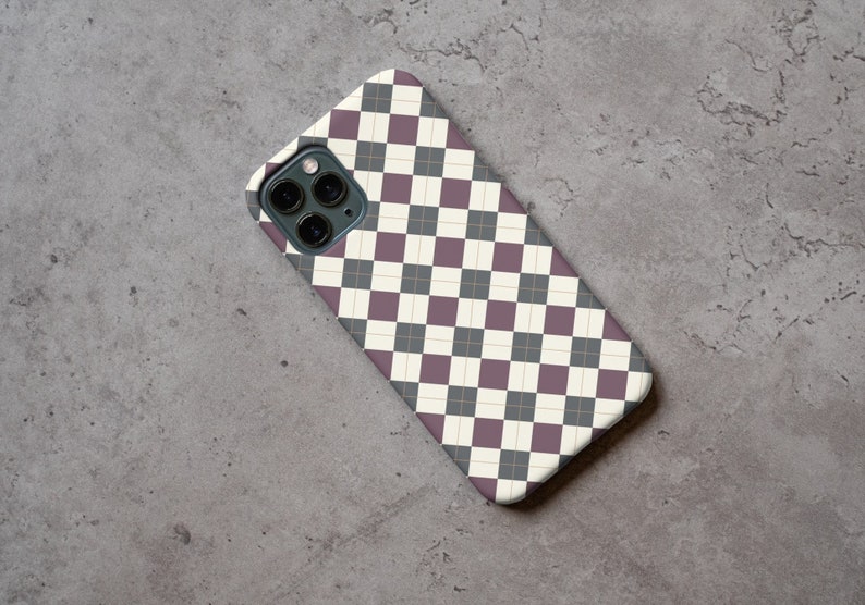 May include: A phone case with a black and white checkered pattern with a thin gold line running through the center of each square. The case has a camera lens cutout in the upper left corner.