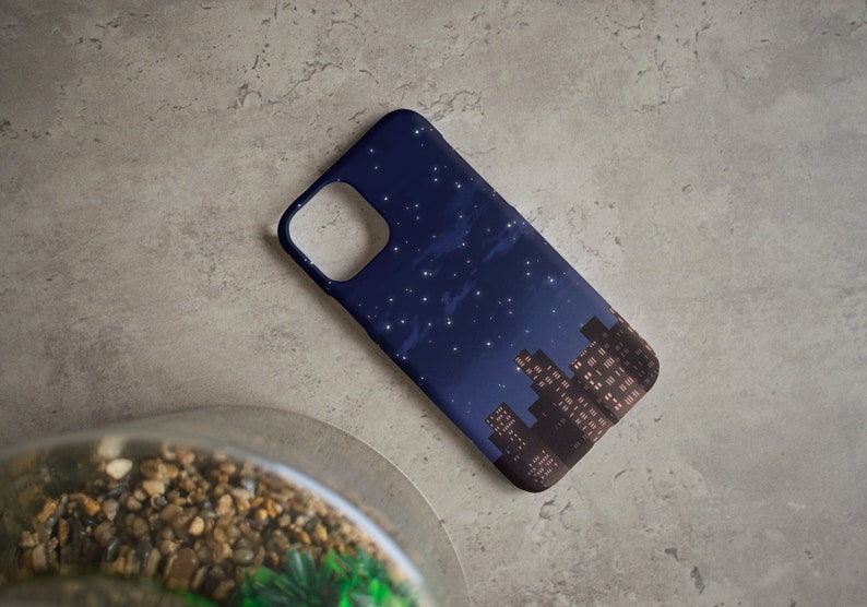 May include: A navy blue phone case with a cityscape silhouette and a starry night sky design. The city lights are visible in the buildings.